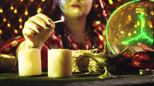 A fortune teller in yellow light lights candles before the start of the session — Stockvideo