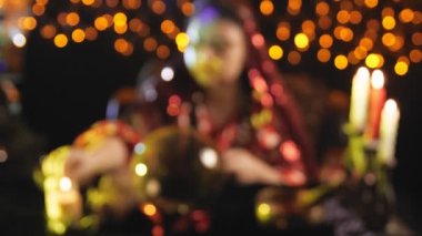 A young brunette fortune teller reads the future by a crystal ball in a blur image salon