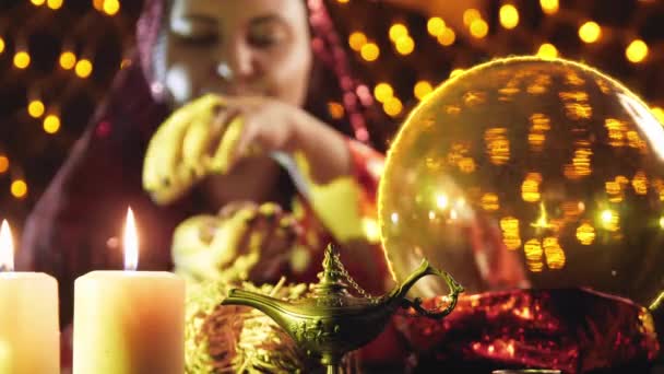 A young sorceress is engaged in magic, reading fate from a small ball by candlelight — Stock Video