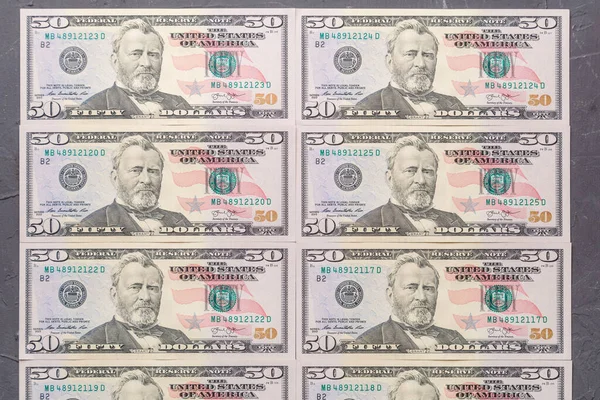 Close-up of fifty dollar bills neatly laid out on a table.