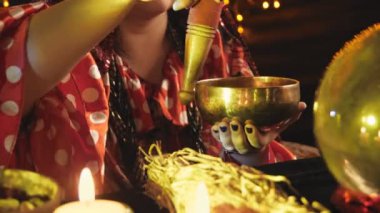 A woman works with a singing bowl by candlelight