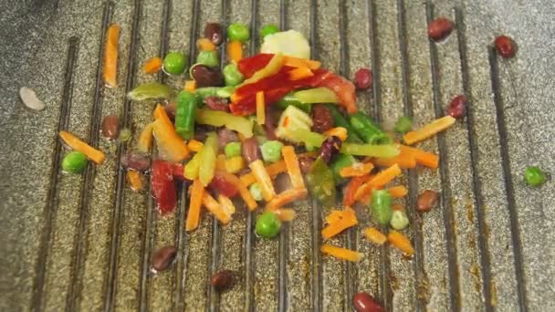 Mrożone warzywa są wlewane do patelni z masłem — Wideo stockowe