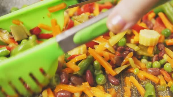 Warzywa smażone na patelni są mieszane z szczypcami powoli mo — Wideo stockowe
