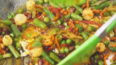 Kızartma tavasında kızartılmış donmuş sebzeler maşayla karıştırılır..
