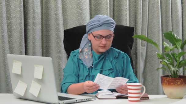 Uma mulher judia em uma cobertura para a cabeça tradicional trabalha em um escritório em casa. — Vídeo de Stock