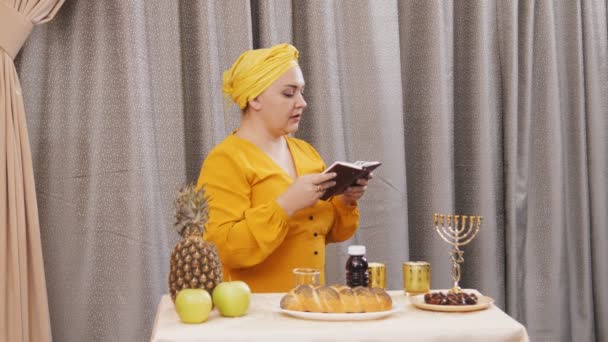 Egy zsidó nő hagyományos fejdísszel felolvas egy szombati imát. — Stock videók