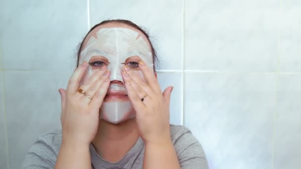 Žena s plátěnou maskou na tváři si masíruje ruce. — Stock video