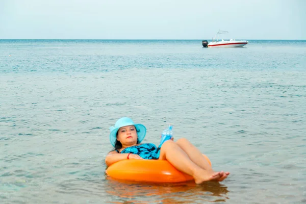 Hasır şapkalı bir kadın ve yüzme çemberindeki gözlüklü bir kadın. Yatay fotoğraf