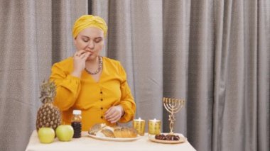 Geleneksel başlıklı Yahudi bir kadın Şabat toplantısından sonra challah yiyor. Genel plan