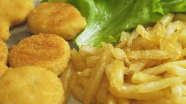 Bir tabak nugget, patates kızartması ve marul yapraklı mısır daire şeklinde döner. yakın plan
