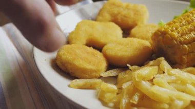 Bir tabak patates kızartması ve mısır nuggetlı eller. Ortam planı
