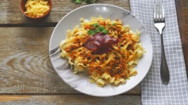 Mendilin üzerindeki ahşap bir masada sebzelerin yanındaki bir tabakta makarna bolonez. Panorama