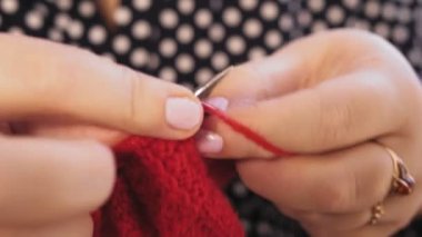 Kadın elleri kırmızı iplikten örgü iğneleri örüyor. Ortam planı