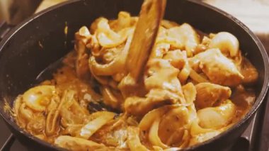 Salamuradaki tavuk parçaları tavadaki bir spatulayla karıştırılmış. Ortam planı