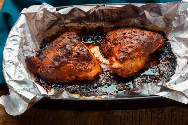 Tabağın üzerinde altın kahverengi bir kabuk ve folyoyla yanmış tavuk..