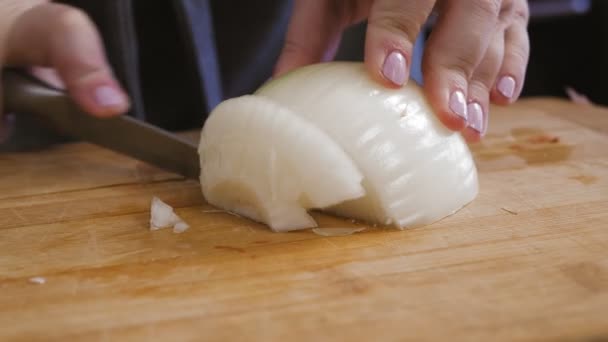 Ženská ruka krájí cibuli nožem na prkně. — Stock video