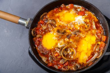 Shakshuka sıcak, gri arka planda kızartma tavasında otlar var.