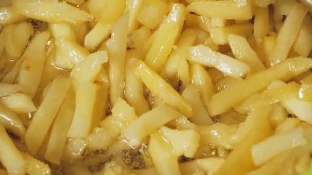 Pommes in einer Pfanne mit kochendem Öl werden mit einer Zange vermischt — Stockvideo