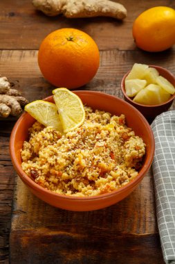 Kurutulmuş meyve ve fındıklı kuskus, masada meyve ve zencefilli kaşığın yanında bir tabakta. dikey resim