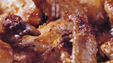 Baharatlar tavuk kanatlarına serpilmiş ve kızgın yağda kızartılıyor. Yavaş çekim