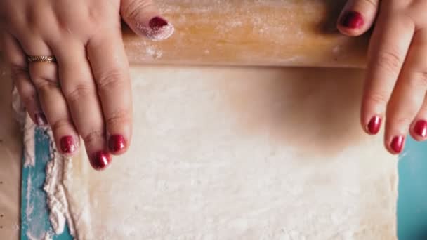 Еврейка на столе выкатывает тесто со скалкой для гоменташа на праздник Пурим — стоковое видео