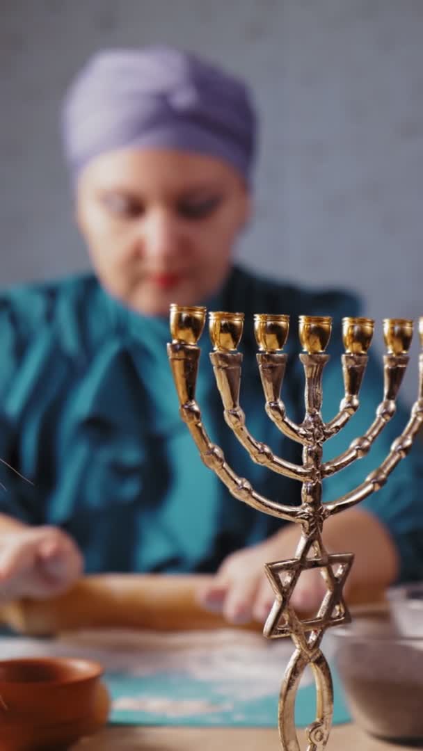 På menorah bordet, en judisk kvinna i en huvudbonad bakom hennes rullar ut deg för Gomentash för Purim i oskärpa — Stockvideo