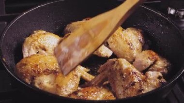 Tavuk kanatları sos ve baharatlarla kızartılır ve bir spatulayla çevirilir.
