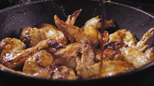 프라이팬에 튀긴 닭고기 날개 위에 간장을 붓는다 — 비디오