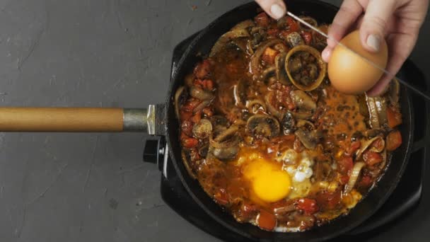 Womens hands break an egg with a knife and dump it into a frying pan with shakshuka — Stock Video