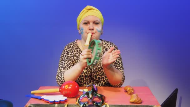 A Jewish woman in a headdress and a carnival mask commands when to make noise in the synagogue on Purim while playing the tympanum during the reading of the scroll — Stock Video