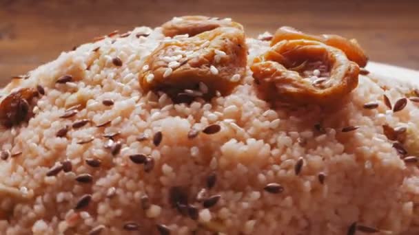 Couscous with dried fruits and orchids sprinkled with saffron rotates in a circle — Stock Video