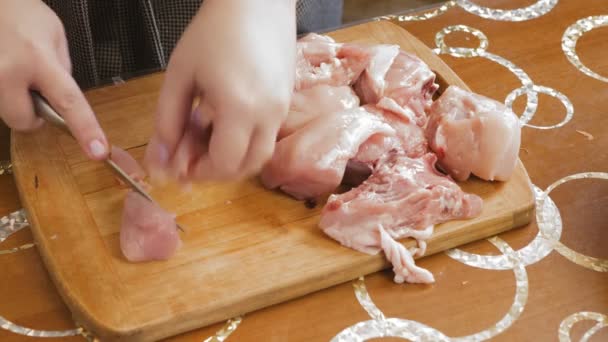 Ένα γυναικείο χέρι κόβει ένα κοτόπουλο σε ένα ξύλο κοπής με ένα μαχαίρι — Αρχείο Βίντεο