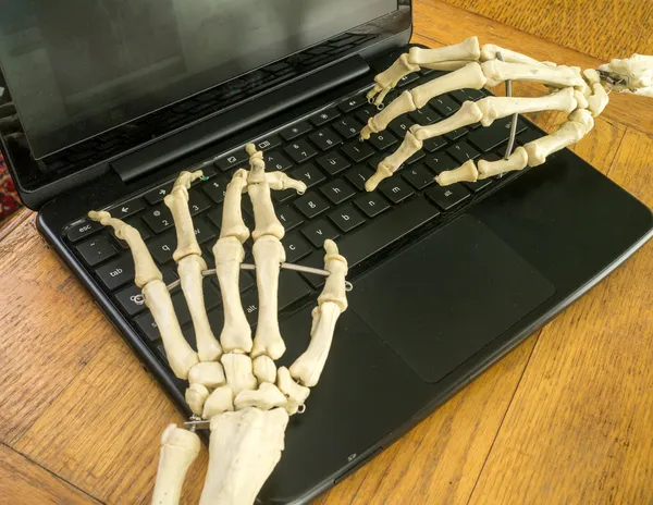 Boney skeleton handen een computer werken — Stockfoto