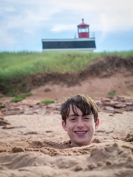 Fun at the beach - boy buried in the sand — Stock Photo, Image