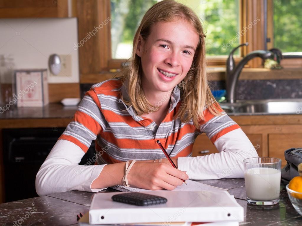 Smiling Young Girl Doing Homework On Table At Home Stock 