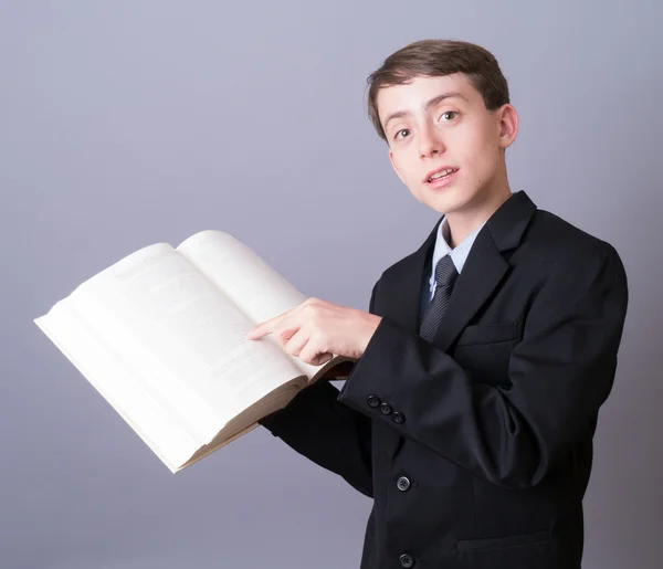 Kid pointing to a passage in a large book — Stock Photo, Image