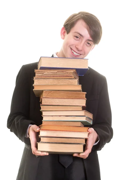 Joyeux adolescent garçon en costume et cravate avec une grande pile de livres — Photo