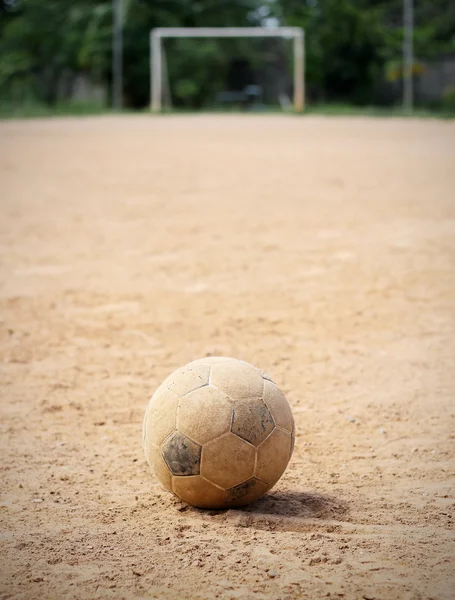 En gammal fotboll på marken, målet är bakgrunden — Stockfoto