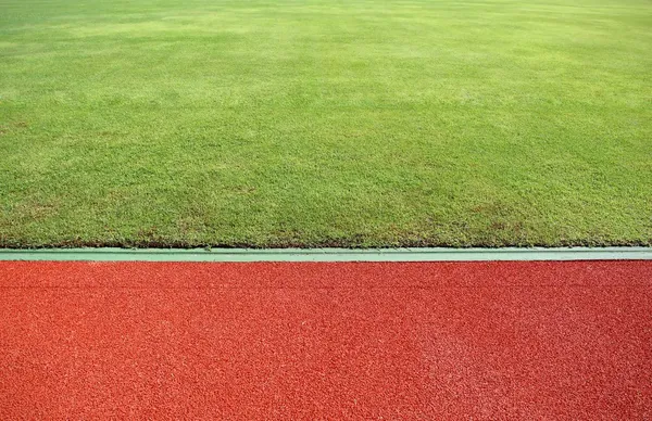 Vista abstracta de pista de atletismo y campo verde — Foto de Stock