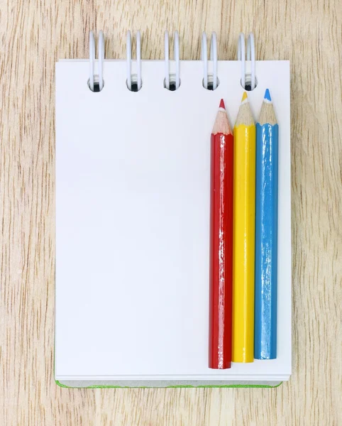 Цветной карандаш и блокнот на дереве — стоковое фото