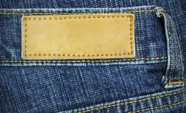 Jeans etiket t için arka plan olarak kullanılan bir kot üzerine dikilmektedir. — Stok fotoğraf