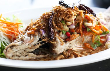 Snapper chili soslu kızarmış ve sebzeler üzerinde beyaz p giyinmiş