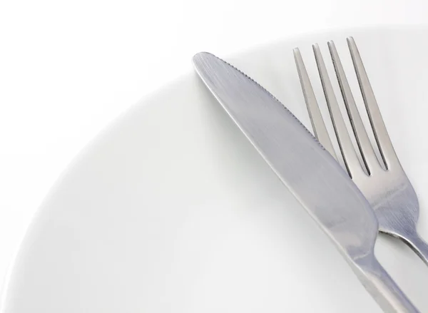 Bílý talíř, vidlička a nůž na bílém pozadí — Stock fotografie
