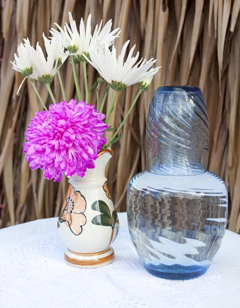 Verre rétro et bouteille avec des fleurs dans un vase sur la table — Photo