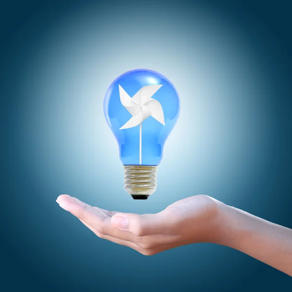 Paper windmill in a blue light bulb on women hand — Stock Photo, Image