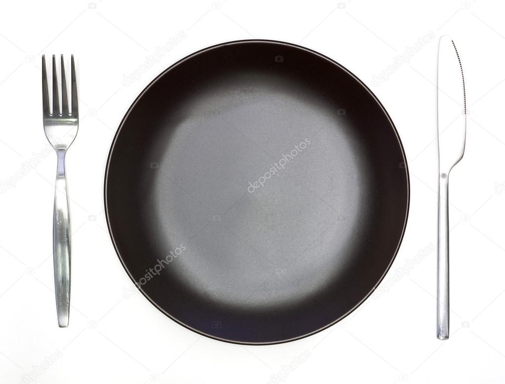 Knife, dark brown plate and fork isolated on white background
