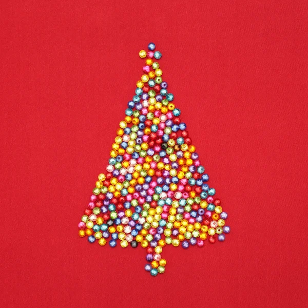 Christmas tree decorate by colorful beads on red background — Stock Photo, Image