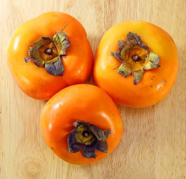 Świeże, dojrzałe persimmon na drewno — Zdjęcie stockowe