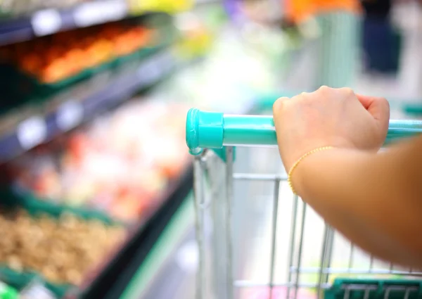 Vrouw hand met winkelwagentje in de supermarkt — Stockfoto