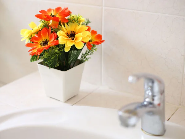 Kunstbloemen op wastafel in een badkamer — Stockfoto